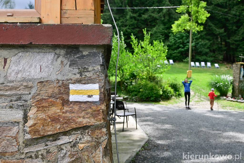 Oznaczenie żółtego szlaku turystycznego na murze schroniska "Pod Muflonem" w Dusznikach-Zdroju