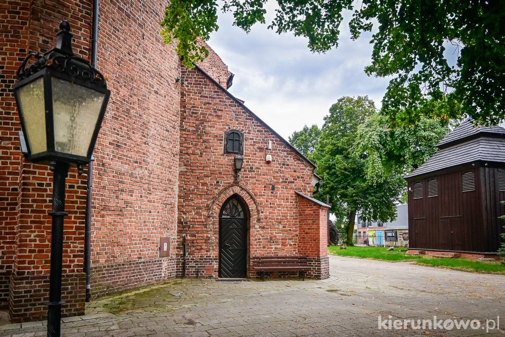 Wejście do kościoła w Kostrzynie, w głębi drewniana dzwonnica